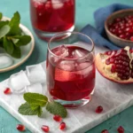 verre de jus de grenade sur fond turquoise avec menthe